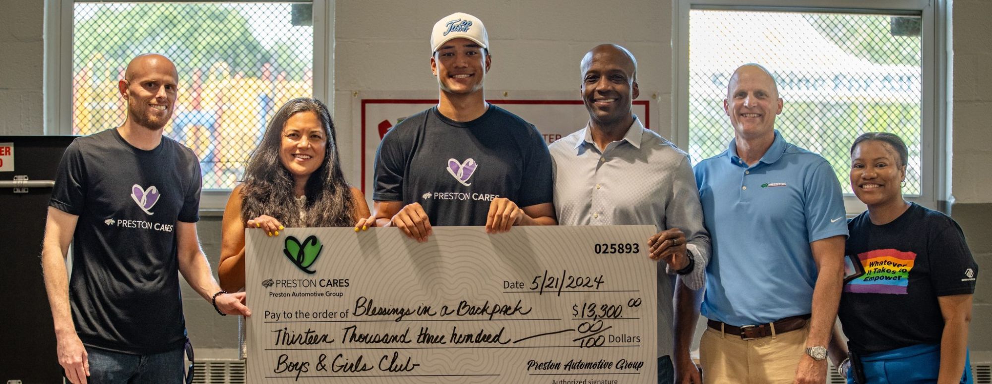 Kyle Hamilton holding a Preston Cares check for Blessings in a Backpack