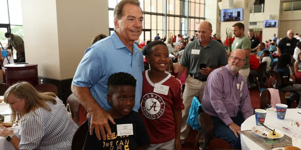 Nick Saban posing with kids at a Nick's Kids Foundation event